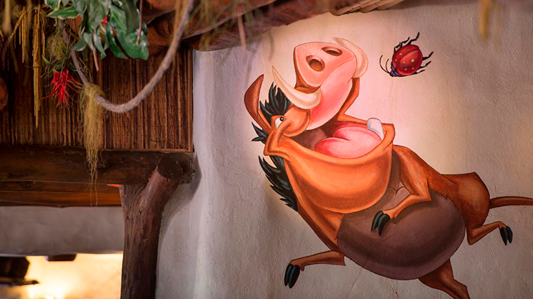 Pumba en Restaurant hakuna matata, rodeada por una decoración western meticulosa y luces suaves que iluminan el espacio.